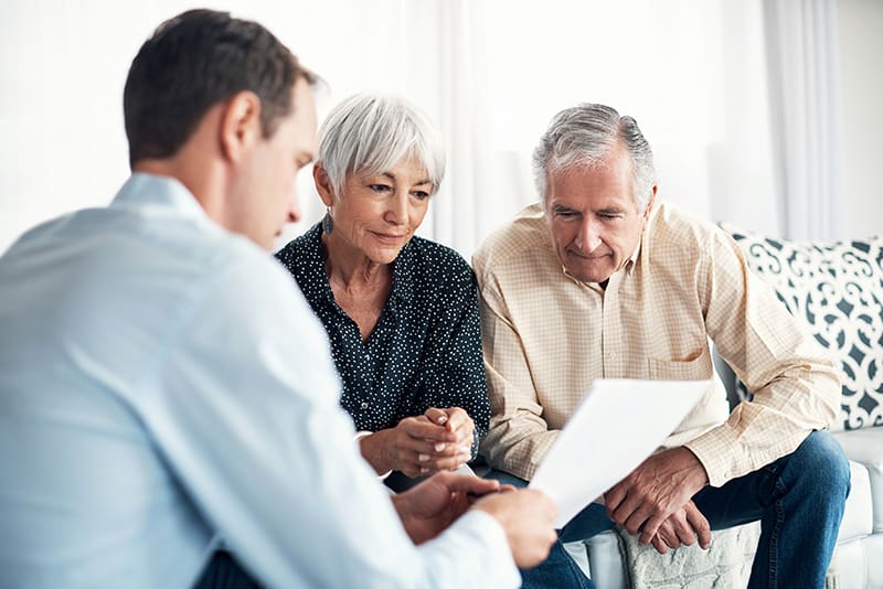 Senior-aged couple reviewing finances with financial planner